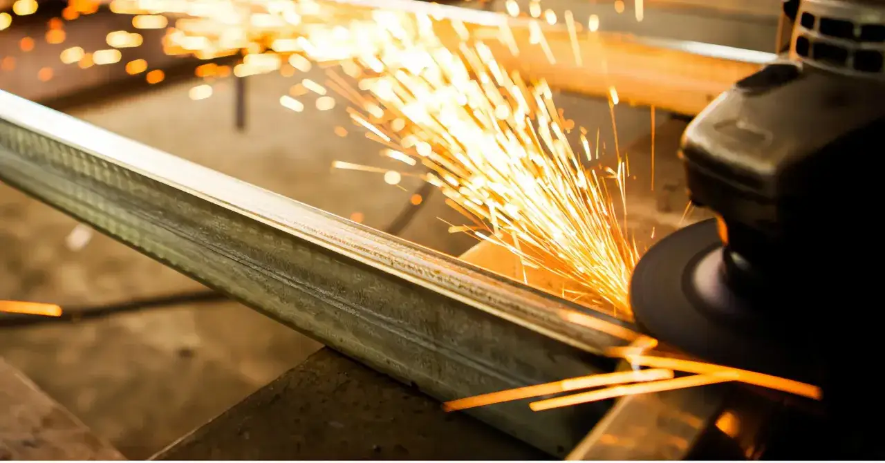 Un disco da taglio genera scintille mentre taglia un profilo metallico, mostrando come tagliare alluminio in modo efficace.