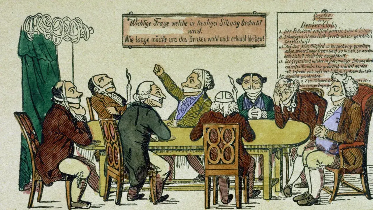 Karikatur zeigt Männer mit Knebeln, die über die Karlsbader Beschlüsse debattieren. Zensur verhindert freie Meinungsäußerung.