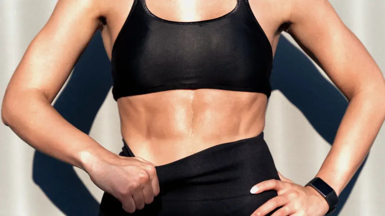 Addominali scolpiti e sudati, frutto di duro allenamento. La definizione dei muscoli addominali è evidente sotto la luce.