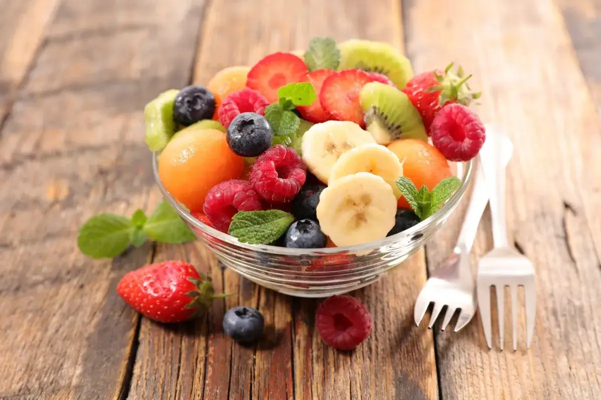 Kolorowa sałatka owocowa z truskawkami, malinami, borówkami, bananami, kiwi i melonem. Idealne składniki, co dodać do sałatki owocowej.