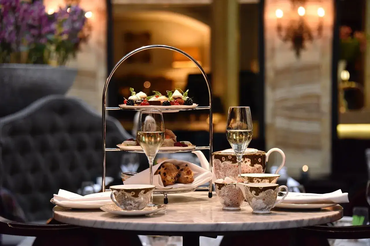 Ett elegant afternoon tea p&aring; Grand Hotel med t&aring;rtfat, glas med bubbel och vackert porslin.