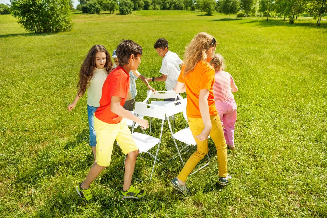 Ni&ntilde;os jugando a las sillas musicales en un d&iacute;a soleado, una de las tem&aacute;ticas para juegos m&aacute;s divertidas.