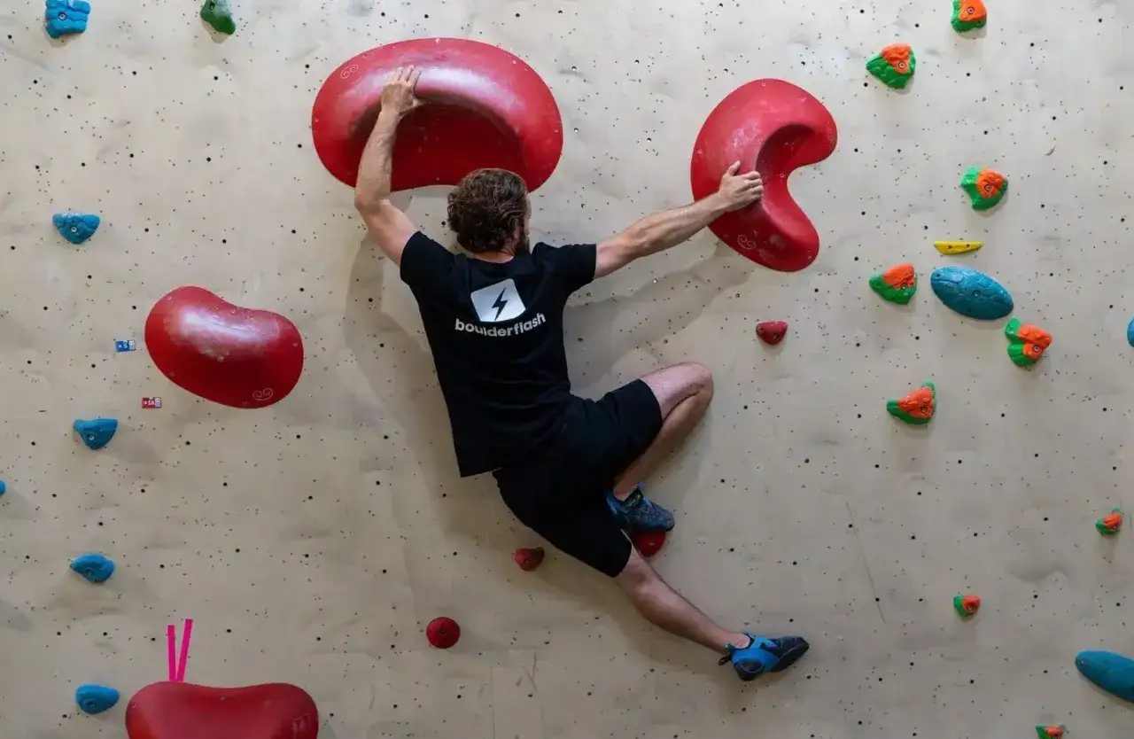 Ein Mann klettert an einer Boulderwand. Das ist, was ist bouldern: eine Herausforderung für Körper und Geist.