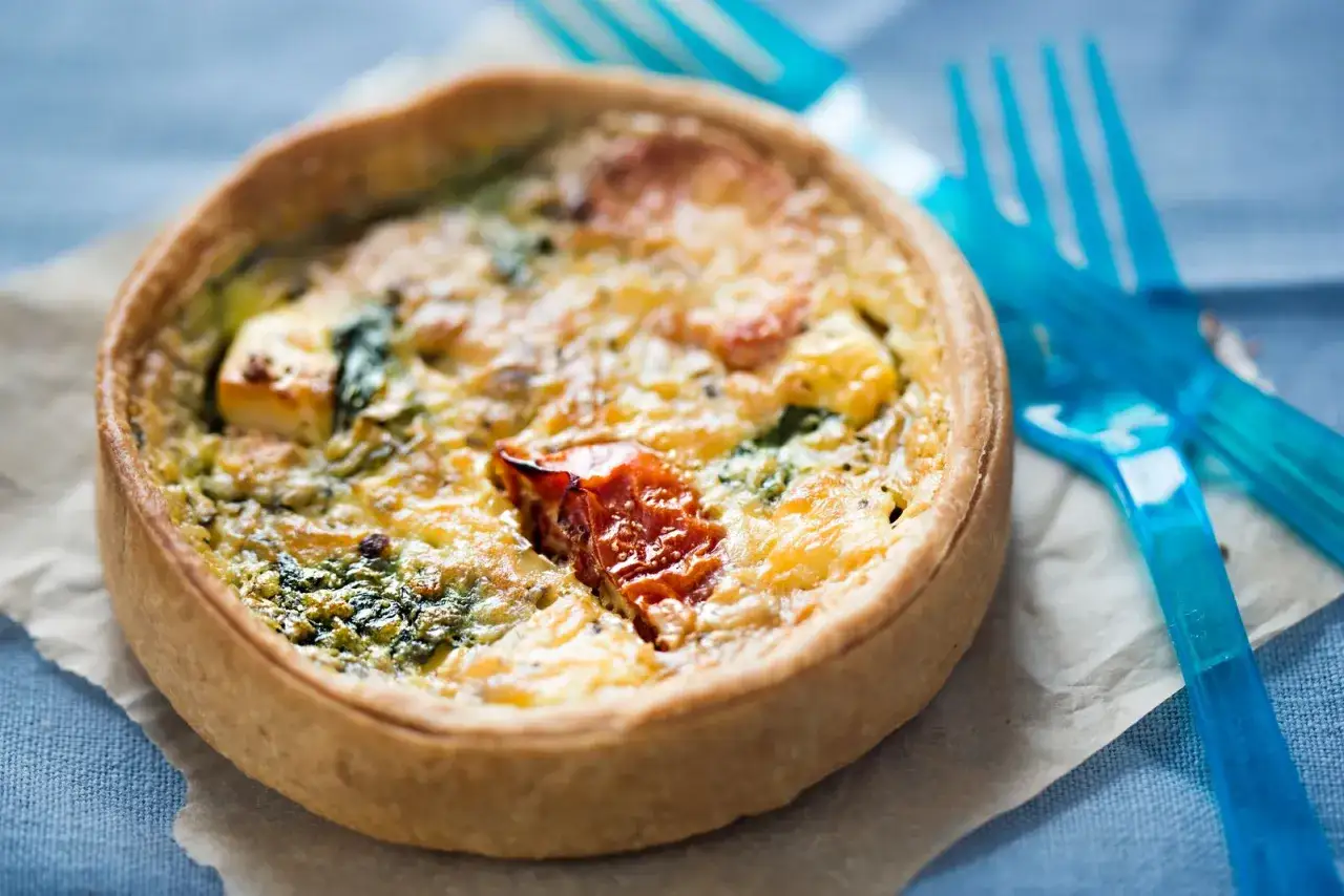 Torta salata in friggitrice ad aria, dorata e ripiena di verdure e formaggio, pronta per essere gustata.