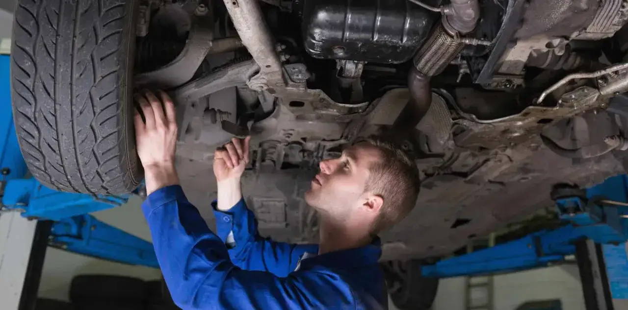 Mechanik bada podwozie auta, szukając oznak zużycia. Słuchaj uważnie, by jak zdiagnozować uszkodzony łącznik stabilizatora na słuch.