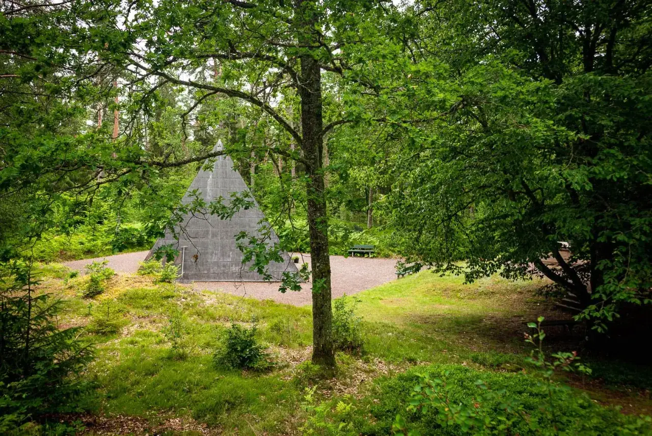 En grå pyramid reser sig ur en lummig skog. En perfekt plats för udda utflykter i Småland, med bänkar för vila.