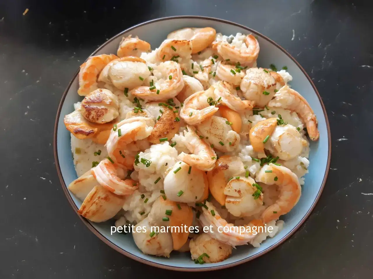 Un délicieux risotto au gambas et Saint-Jacques, garni de ciboulette fraîche.