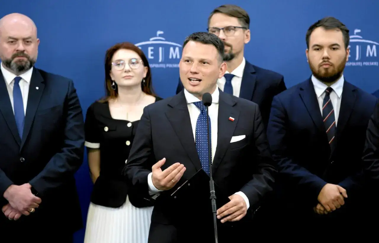 Politycy w garniturach, w tym mówca z mikrofonem, stoją na tle niebieskiej ściany. Spekulacje o wspólnym starcie Konfederacji i Bezpartyjnych Samorządowców.