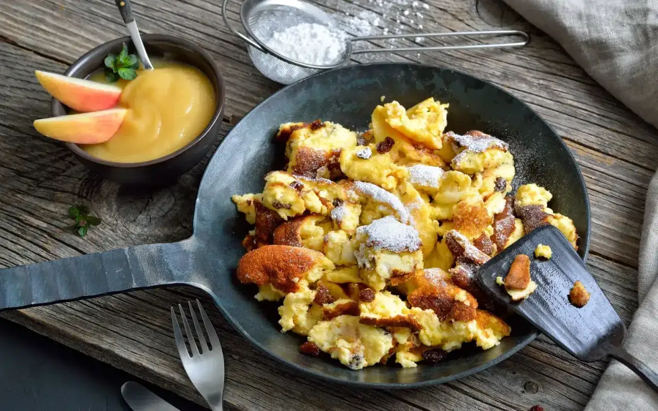 Kaiserschmarrn, ein Klassiker der österreichischen Küche, serviert in einer Pfanne mit Apfelmus. Perfekt für alle, die Schmarrn Rezepte lieben.