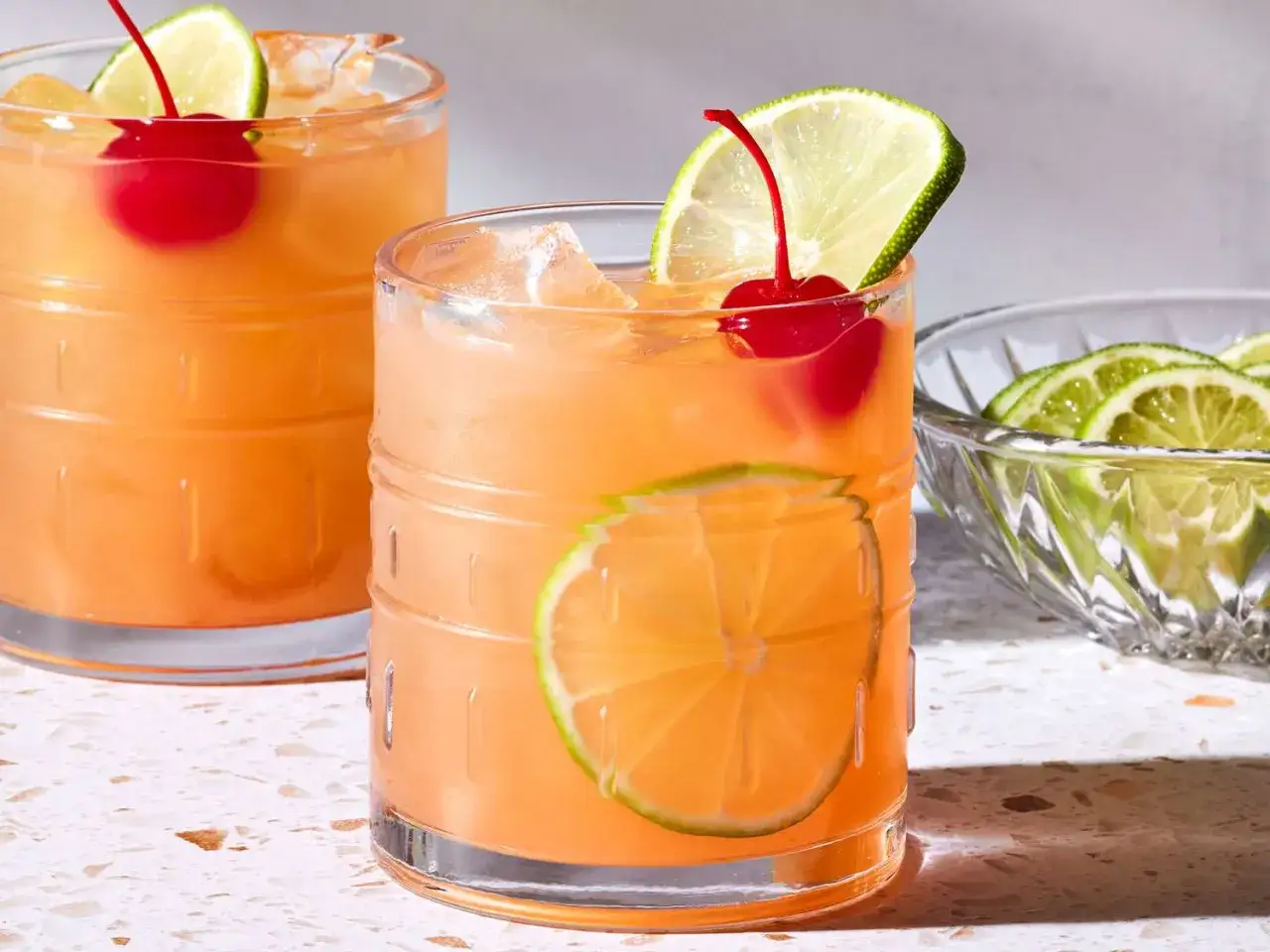 Tv&aring; uppfriskande Mai Tai-drinkar med lime och k&ouml;rsb&auml;r, redo att avnjutas.