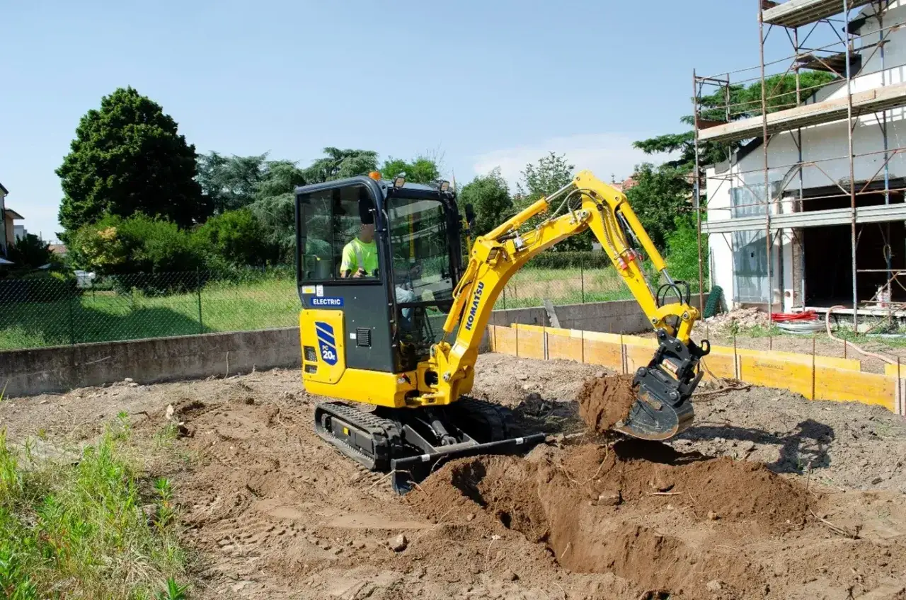 Żółte mini koparki Komatsu pracują na budowie, kopiąc ziemię.