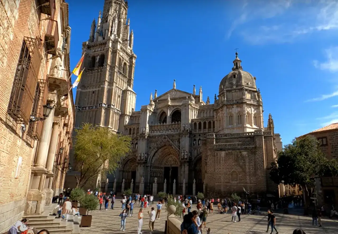 Plaza ante la Catedral de Toledo, ideal para un **free tour Toledo**. Gente paseando bajo el sol.