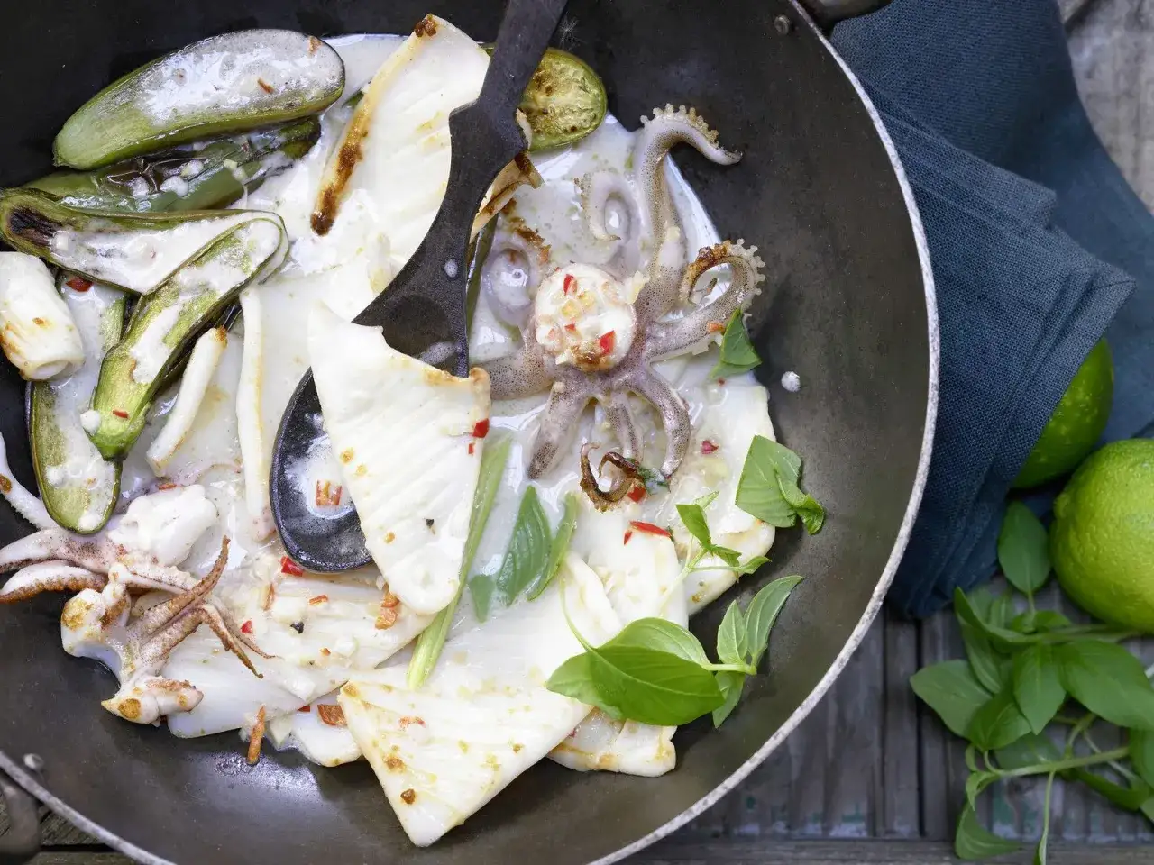 Tiefgefrorene Calamari zubereiten in der Pfanne mit Kokosmilch, Auberginen und frischem Basilikum.