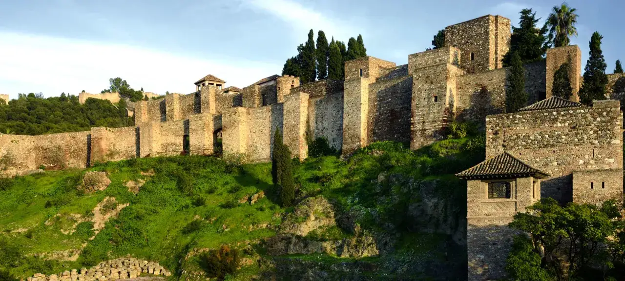 Les remparts de l'Alcazaba, un site incontournable pour visiter Malaga, se dressent sur une colline verdoyante.
