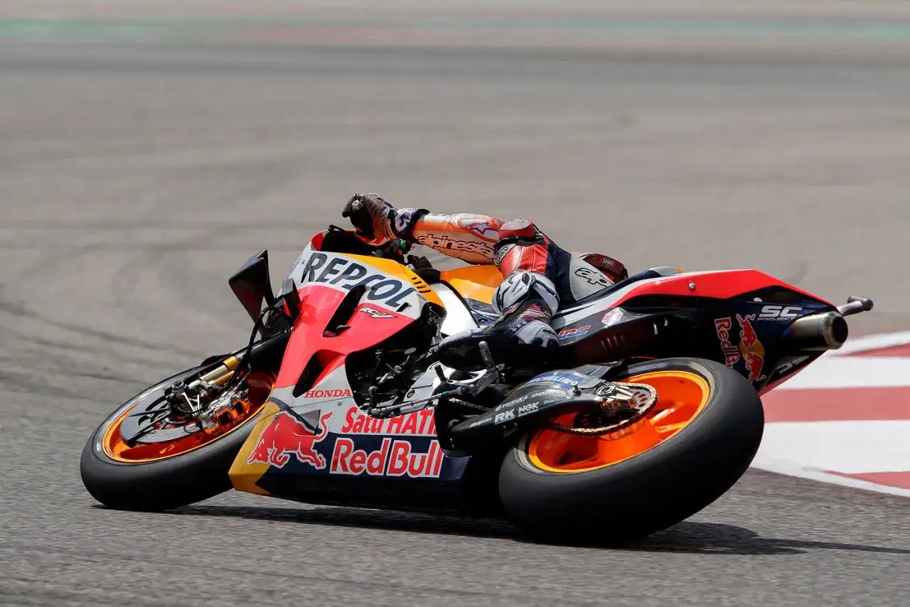 Piloto de MotoGP inclinado en curva, mostrando la potencia de la moto GP con patrocinadores Repsol y Red Bull.