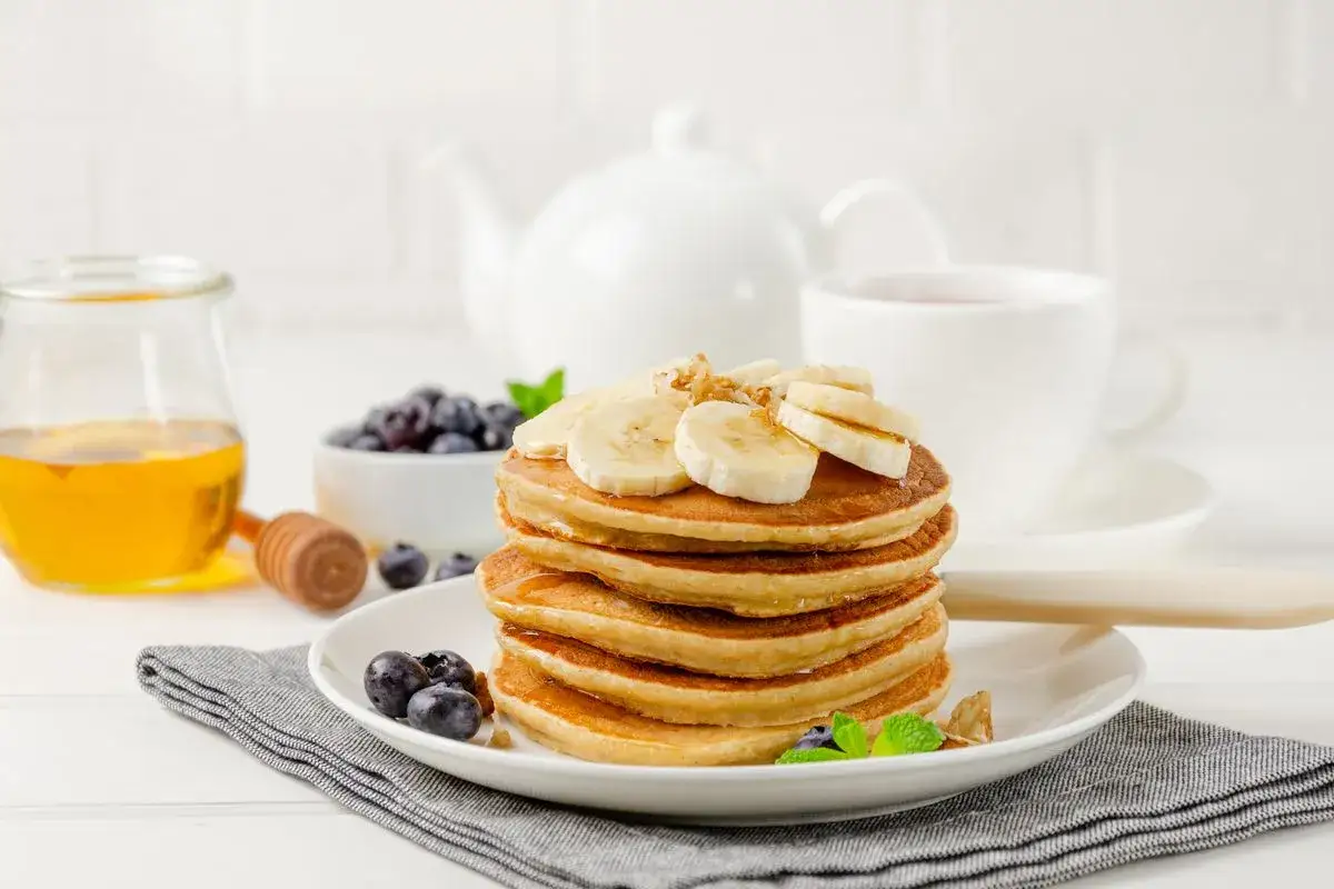 Pancake perfetti, cotti nella friggitrice ad aria, guarniti con banane e mirtilli, pronti per una colazione deliziosa.