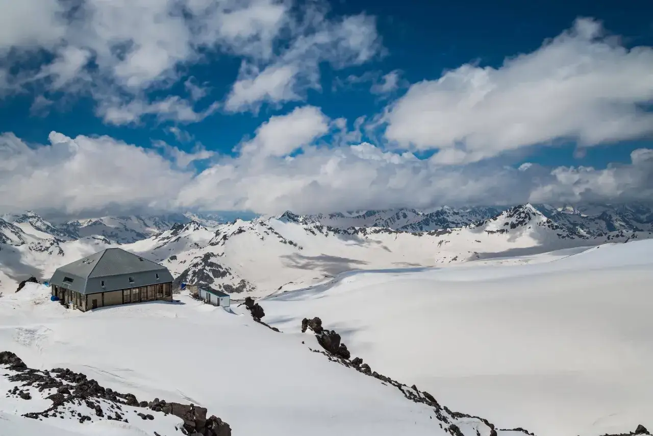 Góry pokryte śniegiem, schronisko i mały domek. Widok na majestatyczne szczyty, przypominające o wysokości najwyższego szczytu w Europie, Mont Blanc, który ma 4810 m.