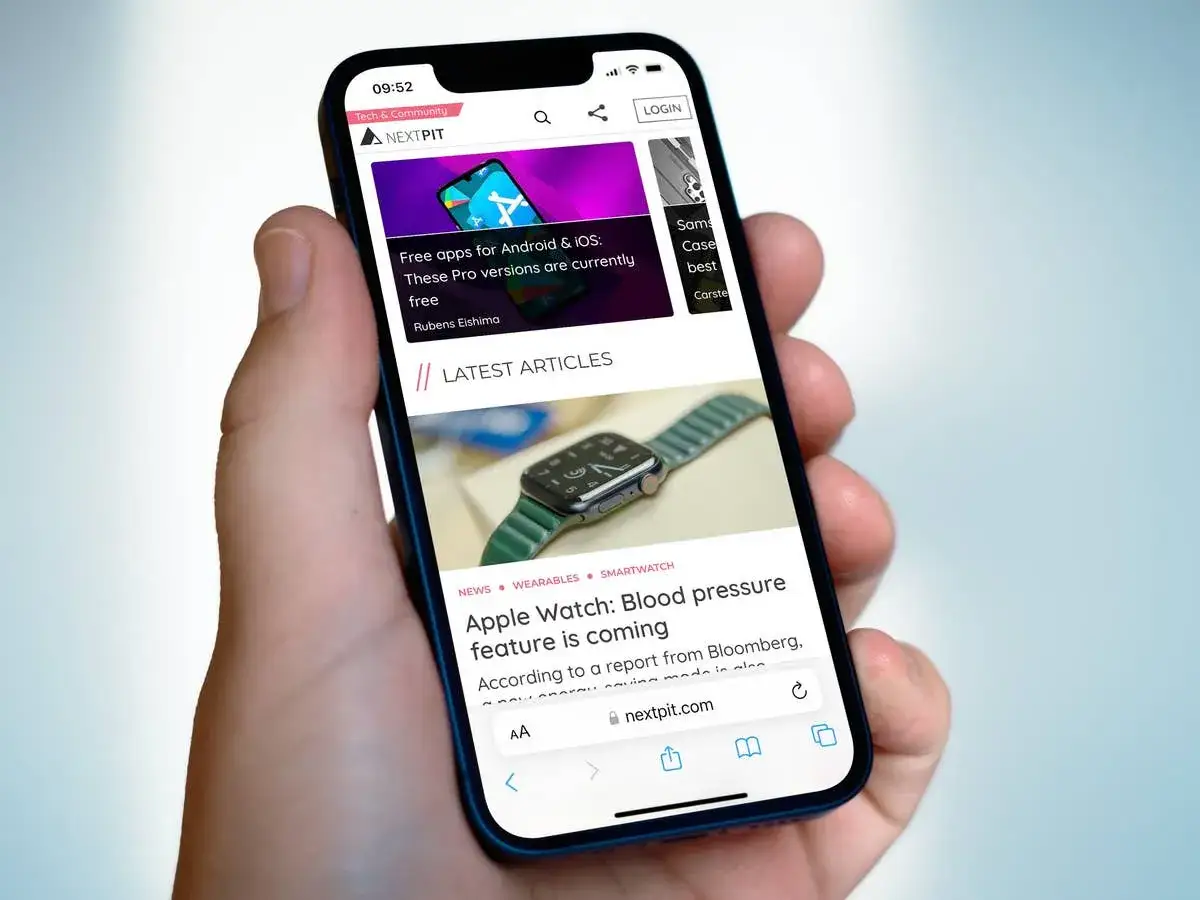 Hand h&auml;lt Smartphone mit ge&ouml;ffneter Webseite. Oben ist die Safari suchleiste. Artikel &uuml;ber Apple Watch und kostenlose Apps.