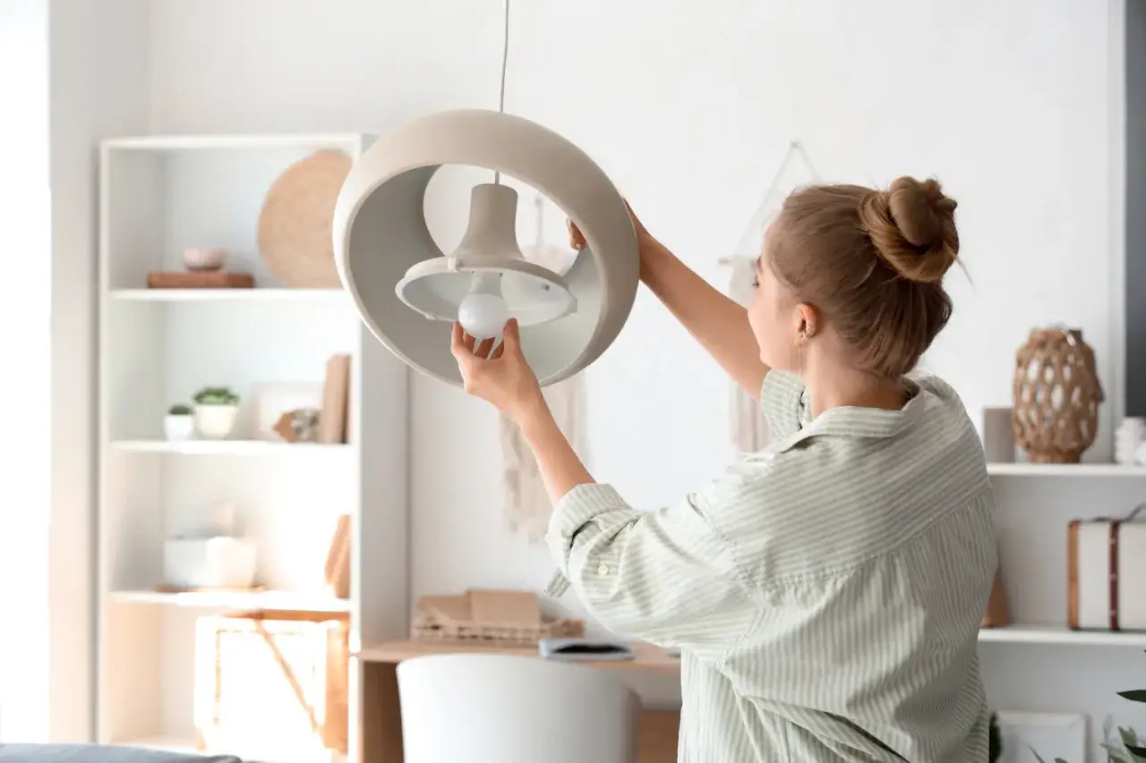 Mujer instala bombilla LED en l&aacute;mpara, un paso para como automatizar las luces de mi casa.