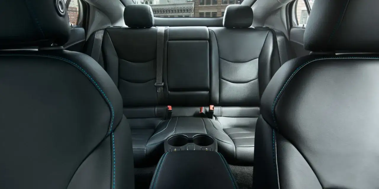 Wnętrze Chevrolet Volt z czarną skórzaną tapicerką i niebieskimi szwami. Widok na tylne siedzenia i podłokietnik z uchwytami na kubki.