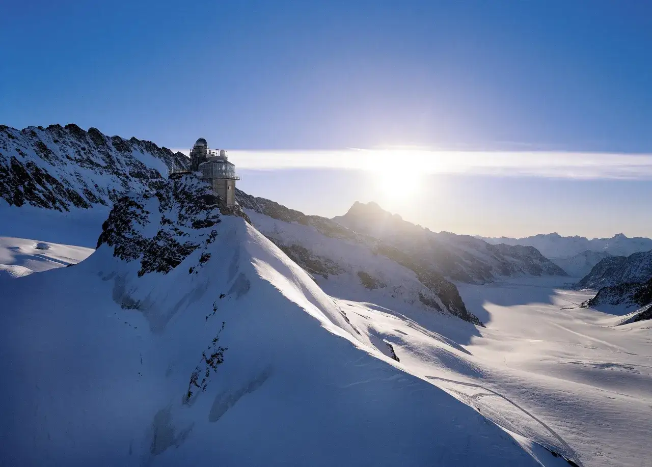 A modern observatory building perched on a snowy mountain peak, offering breathtaking views of the surrounding Alps. This is the top of Europe altitude, a place of stunning natural beauty.