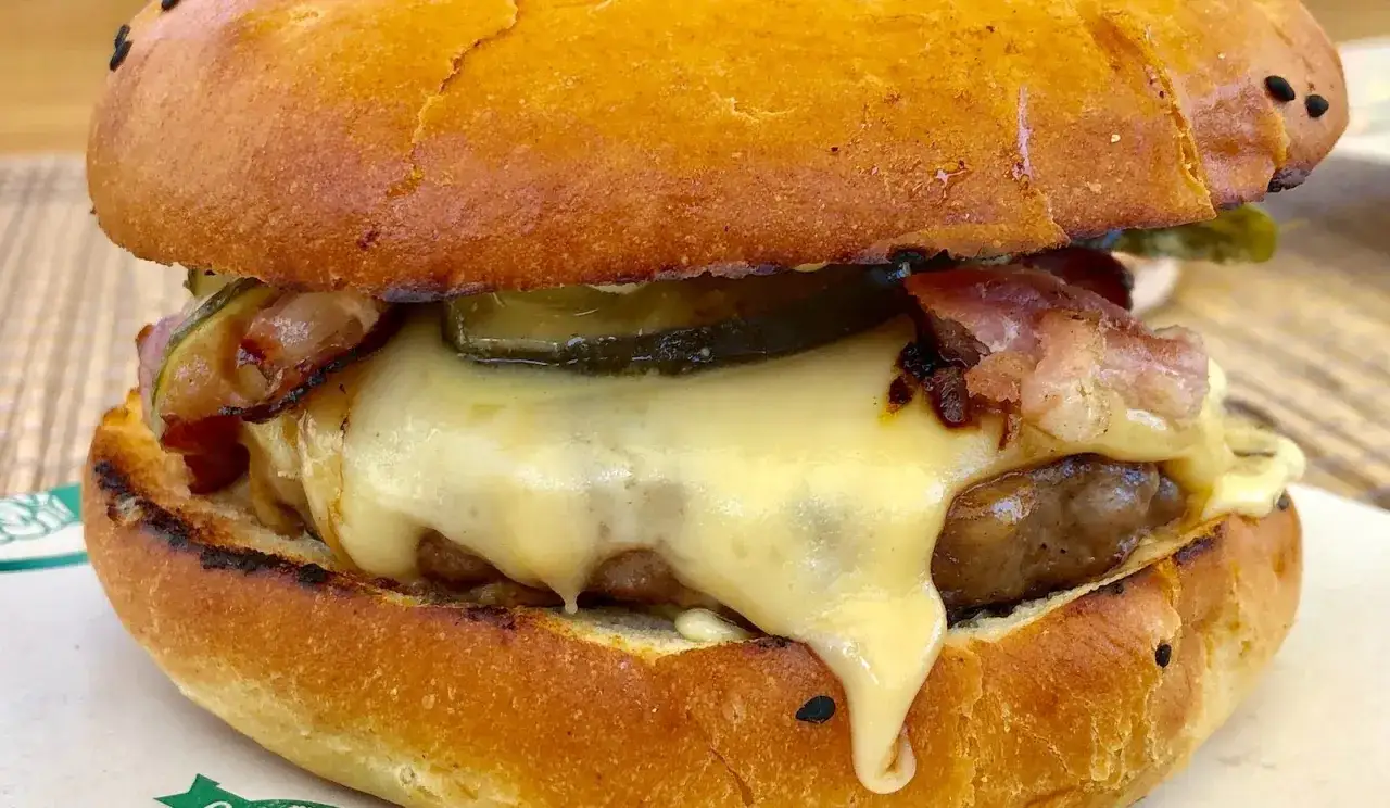 Pyszny burger z dzika z rozpływającym się serem, chrupiącym boczkiem i piklami. Idealny na głodny dzień!