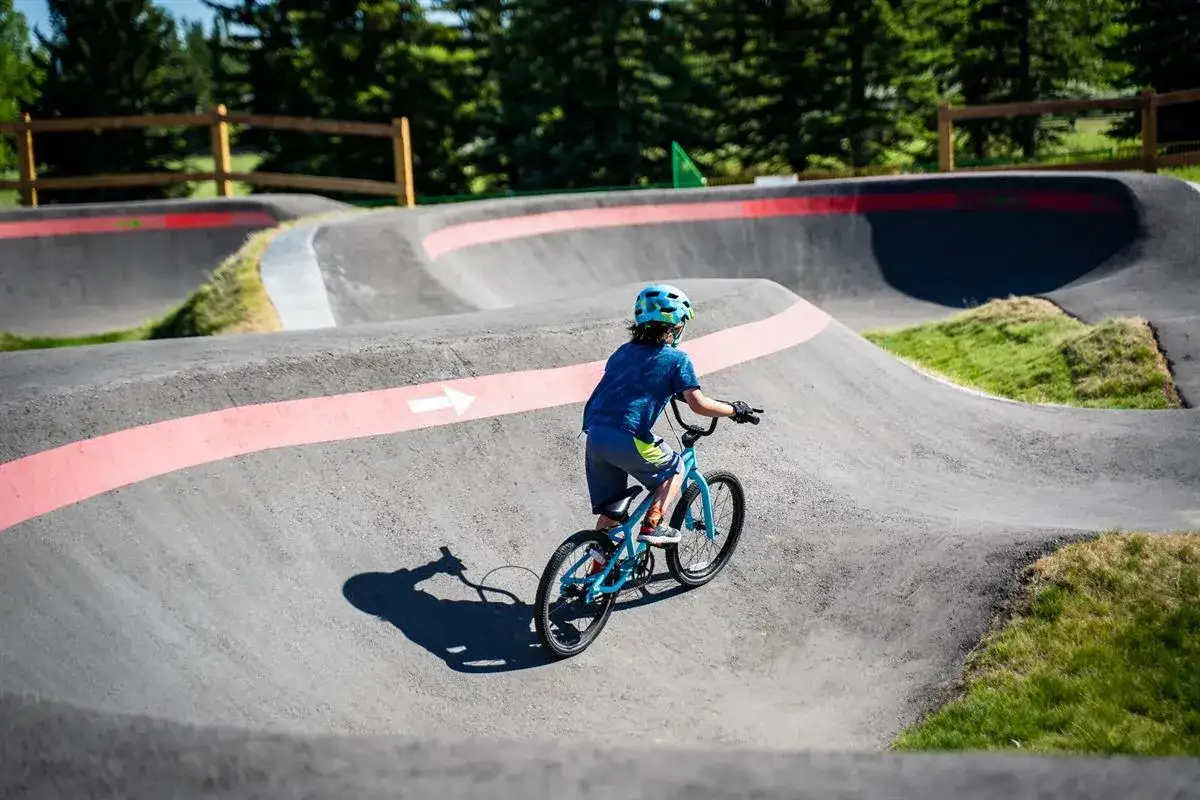 Chłopiec na rowerze pokonuje zakręty na pumptracku, ciesząc się jazdą po falistym torze.