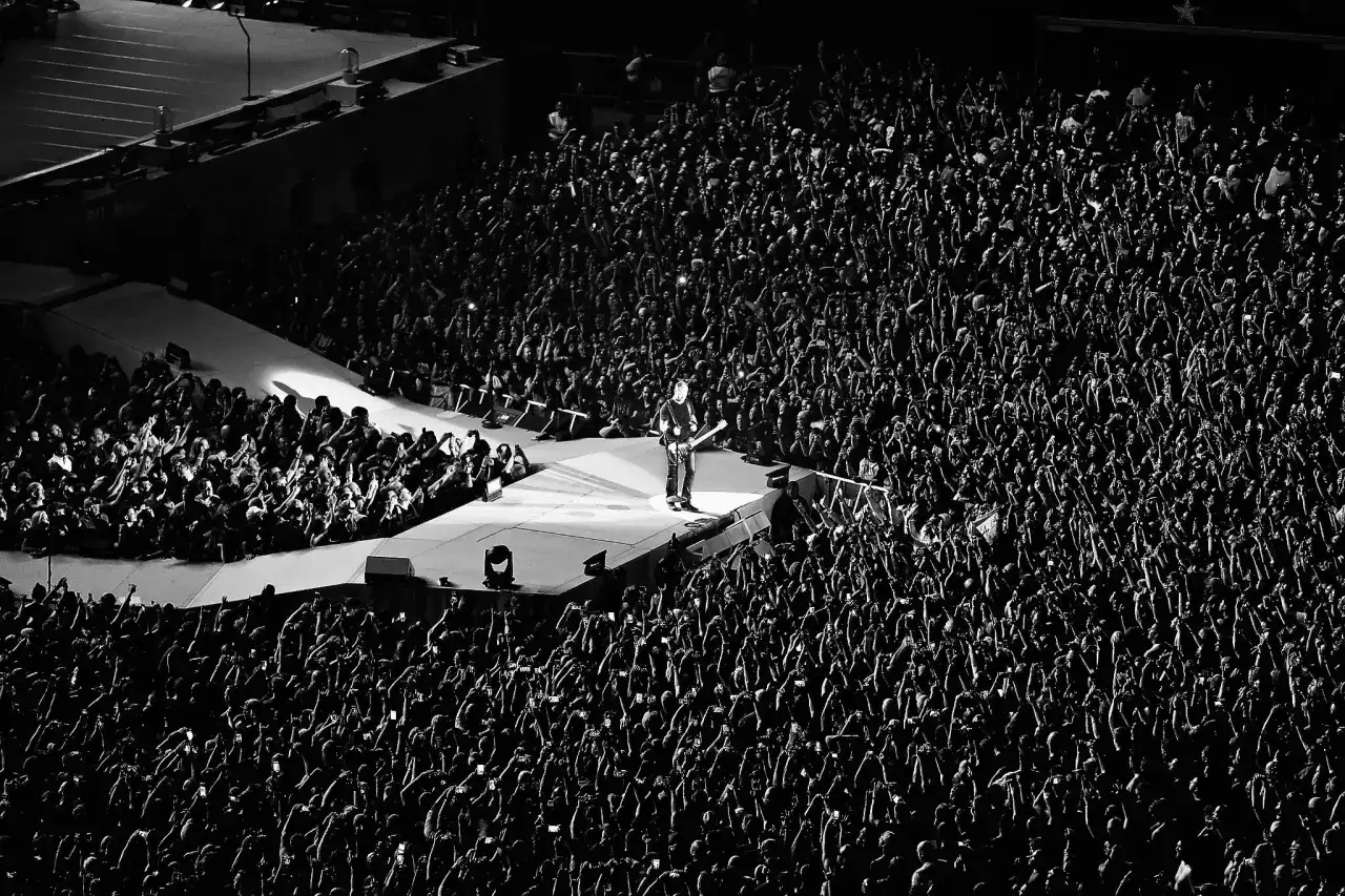 Un guitariste seul sur sc&egrave;ne, entour&eacute; d'une foule immense aux mains lev&eacute;es. L'&eacute;nergie d'un concert du premier groupe de metal.