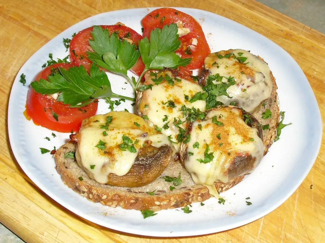 Gef&uuml;llte Champignons auf Brot mit geschmolzenem K&auml;se und Tomaten, ein k&ouml;stliches Gericht, das sich gut f&uuml;r Champignons Rezepte eignet.