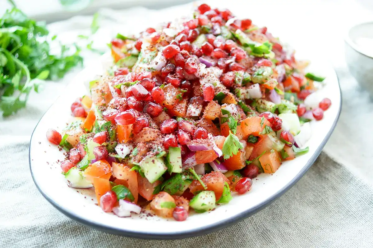 Frischer persischer Salat mit Granatapfel, Tomaten, Gurken und Kräutern, bestreut mit Sumach.