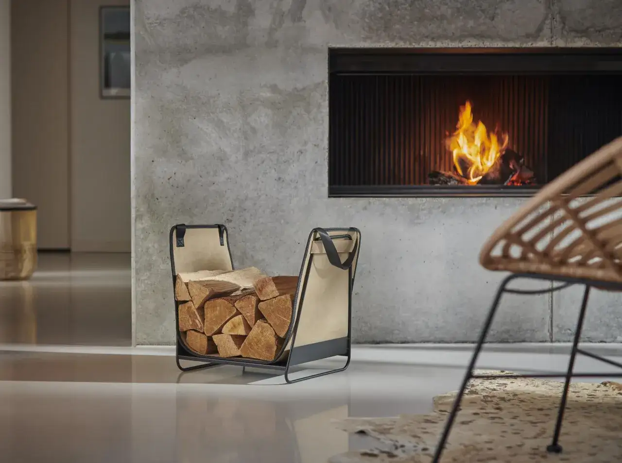 Un panier à bois moderne près d'une cheminée crépitante, prêt à alimenter le meilleur chauffage d'appoint pour une soirée cosy.