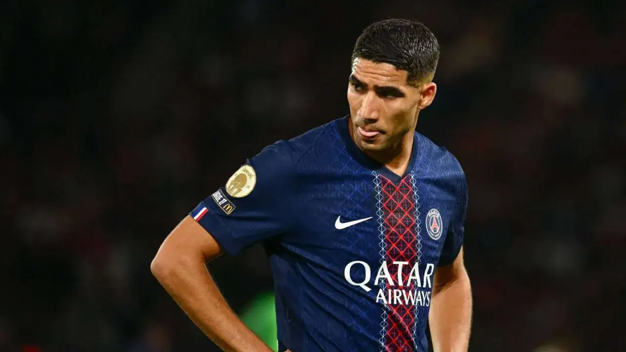 Achraf Hakimi im PSG-Trikot, mit leicht herausgestreckter Zunge, blickt nach rechts.