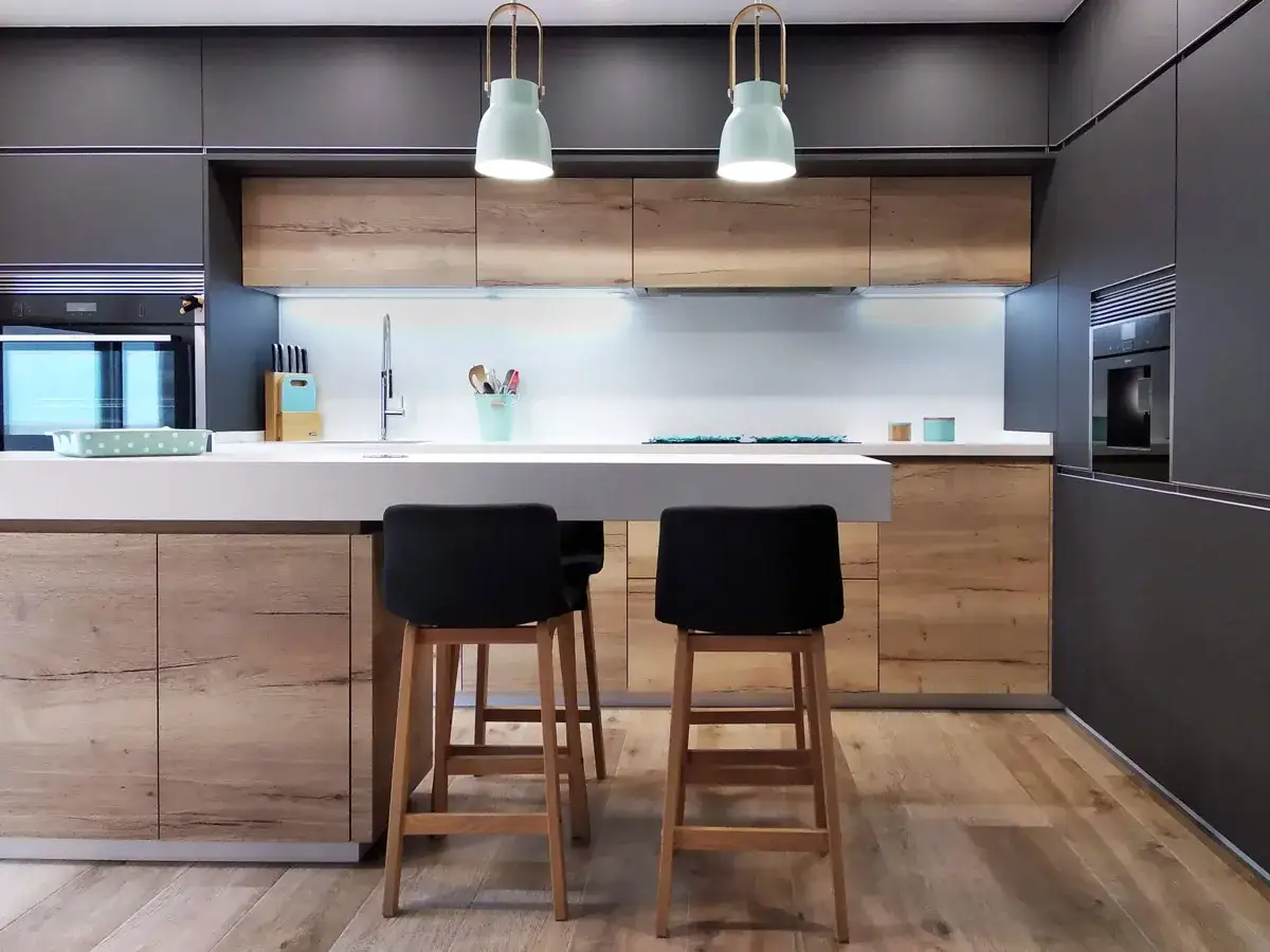 Cocinas peque&ntilde;as con isla, modernas y funcionales, con encimera blanca, taburetes negros y armarios de madera.