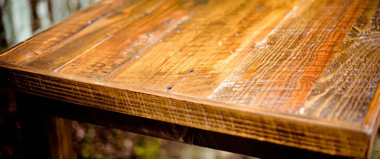 Surface d'une table en bois recycle, aux teintes chaudes et à la texture marquée.
