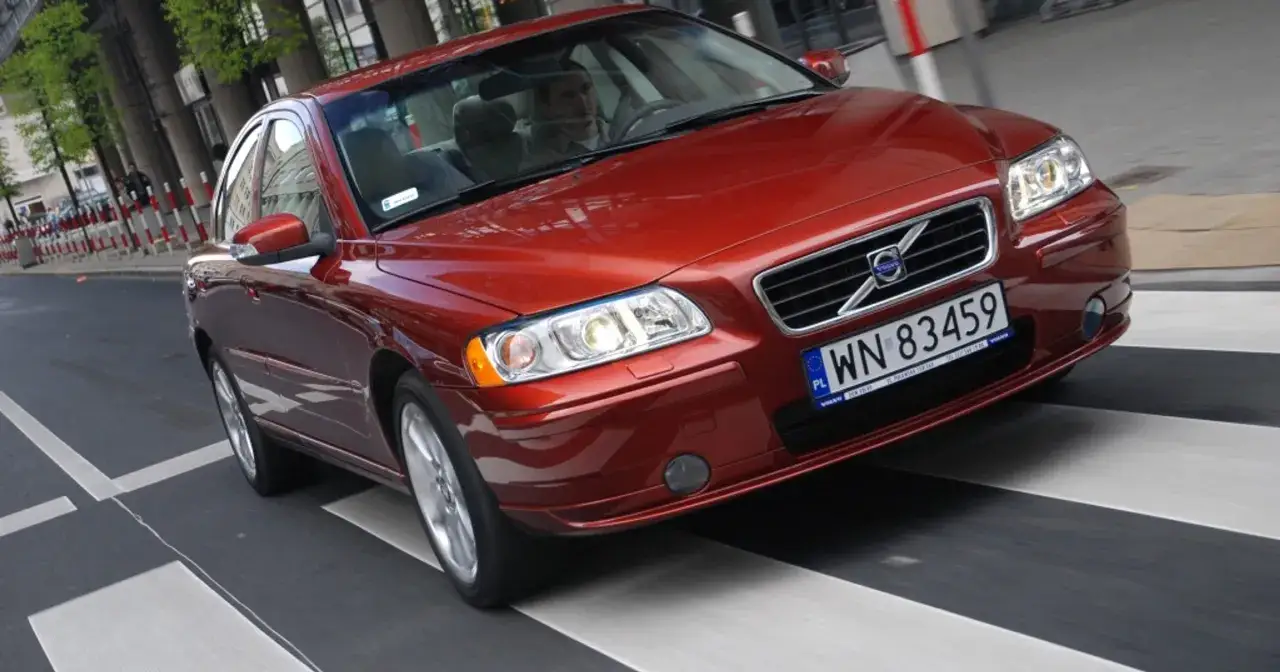 Czerwone Volvo S60 pokonuje pasy na ulicy. Silnik 2.5 turbo pracuje płynnie, zapewniając dynamikę.