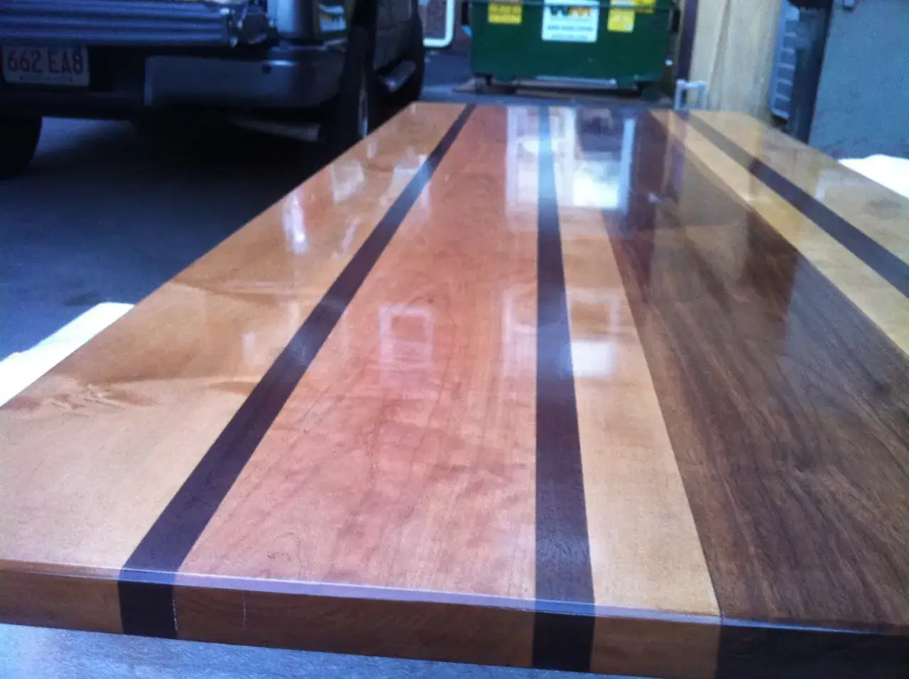 Table en bois aux bandes contrastées, finition brillante après lustrage bois.