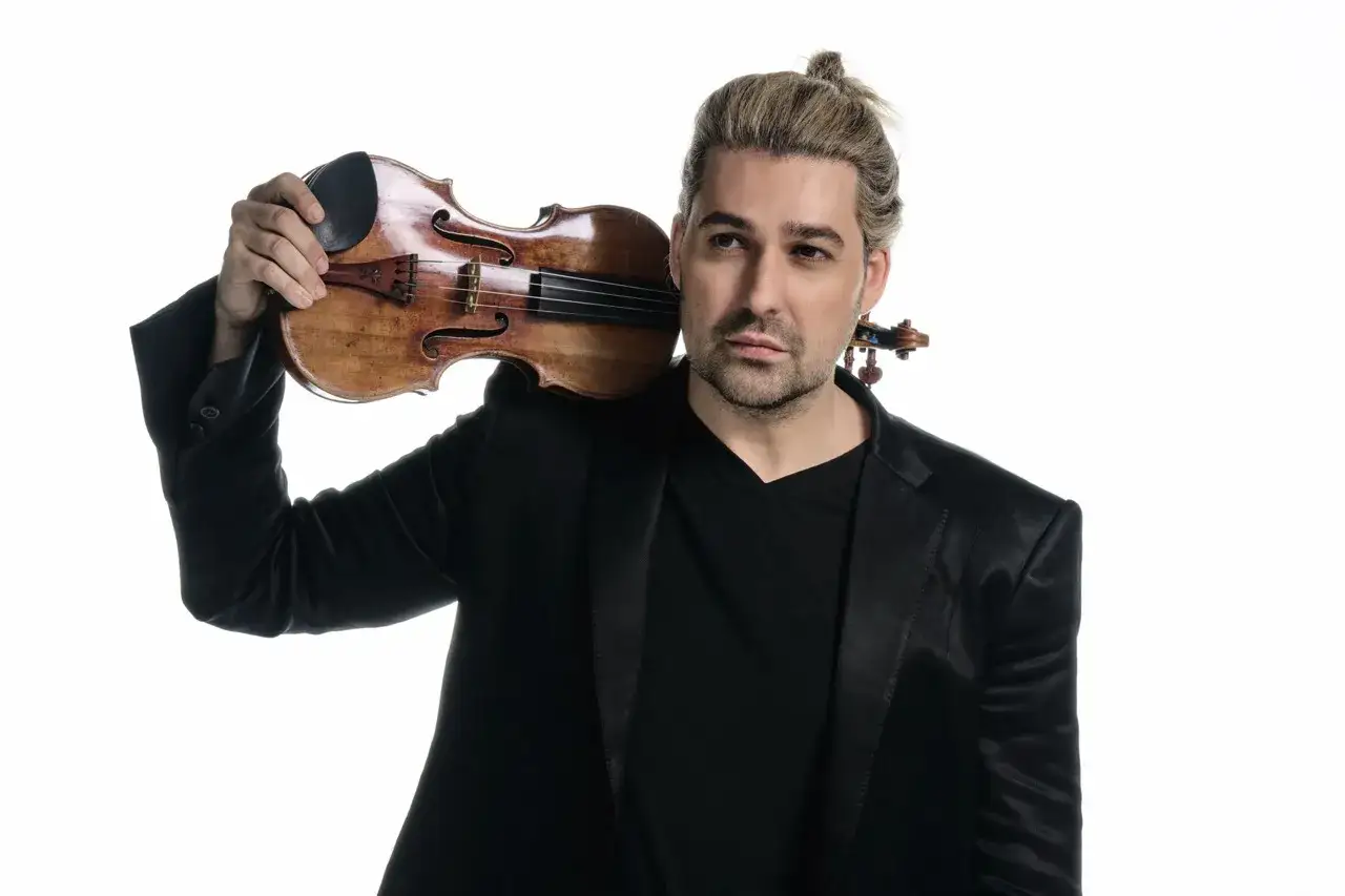 David Garrett w czarnym garniturze trzymający skrzypce na ramieniu.