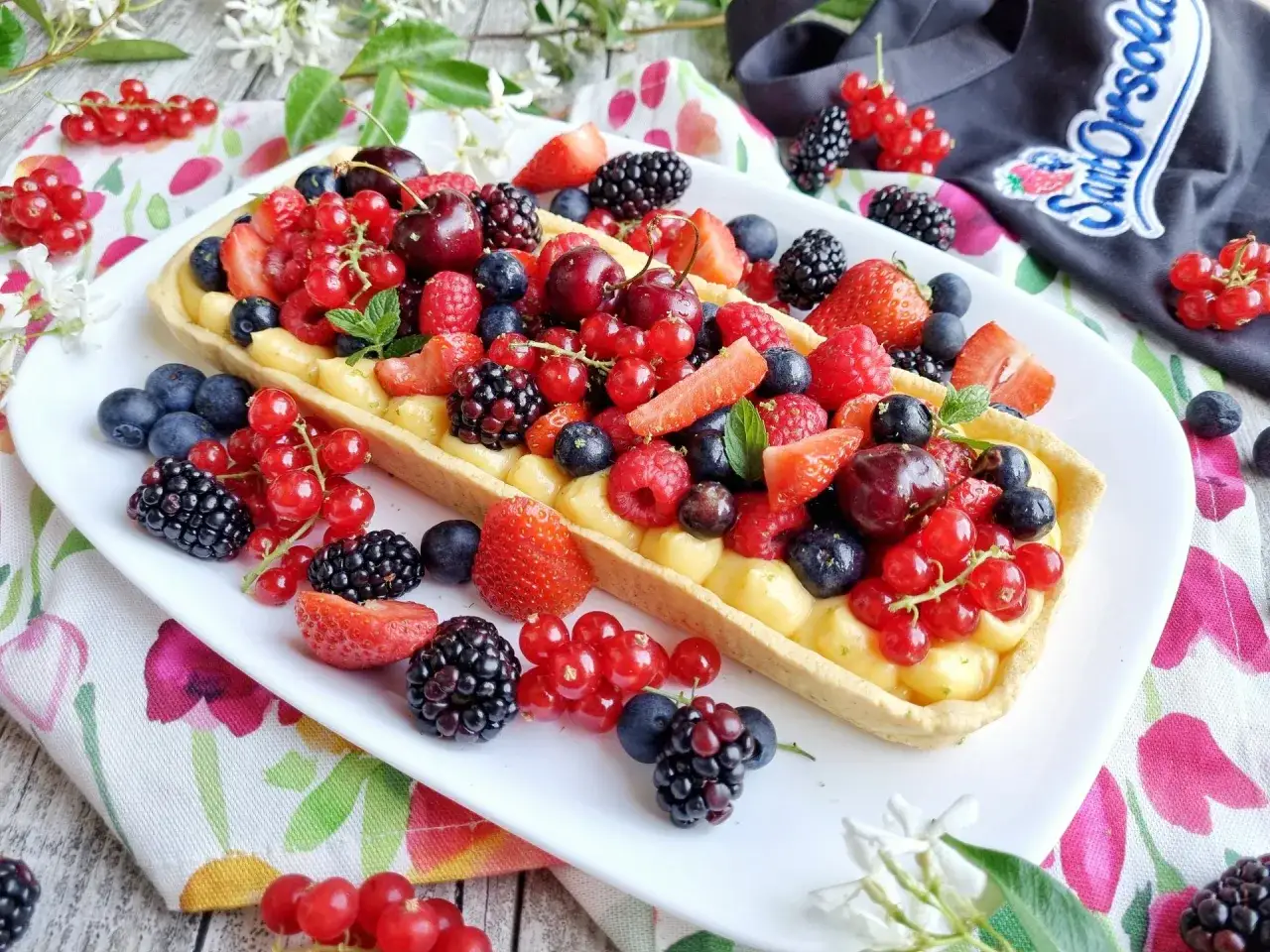 Deliziosa crostata senza glutine ripiena di crema e ricoperta da un tripudio di frutti di bosco freschi: fragole, lamponi, mirtilli, ribes e ciliegie.