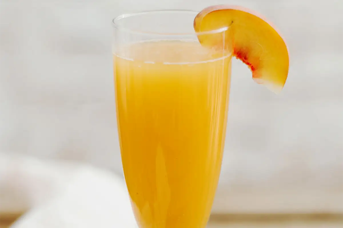 Ein Glas Bellini mit Pfirsichspalte. So einfach ist es, wie man Bellini trinkt.