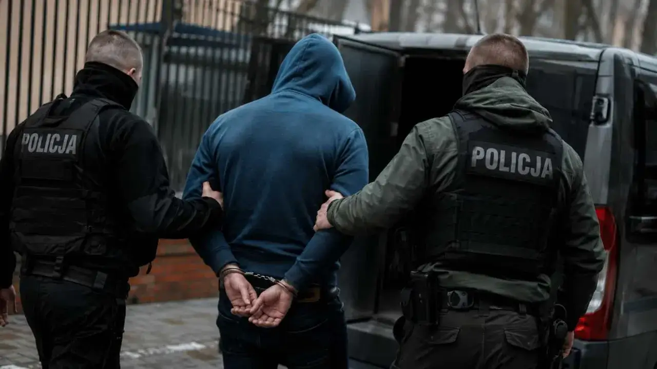 Policjanci zatrzymują mężczyznę w kajdankach. Akcja związana z przeciwdziałaniem narkomanii, zgodnie z art. 62 ust. 1 ustawy.