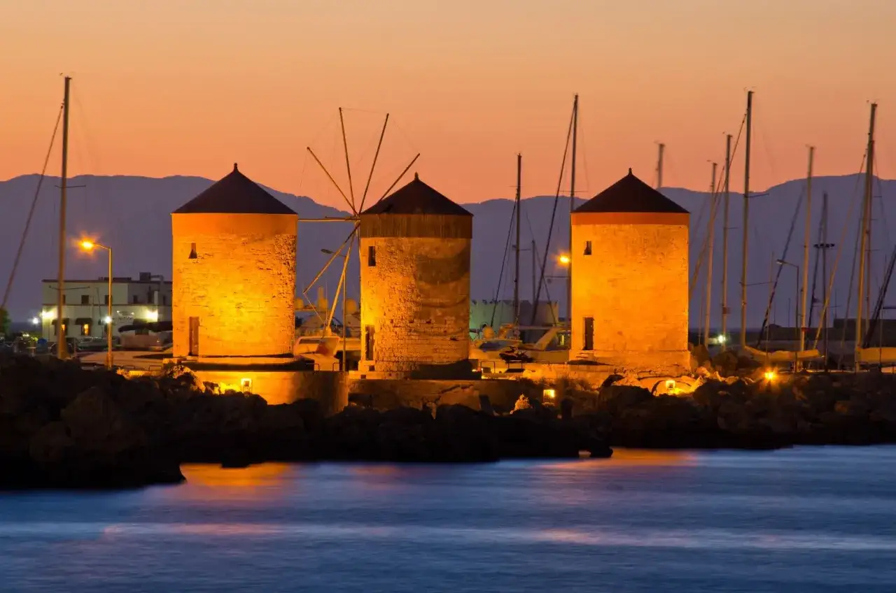 Drei beleuchtete Windm&uuml;hlen am Hafen von Rhodos bei Sonnenuntergang. Ein absolutes Rhodos Must See!