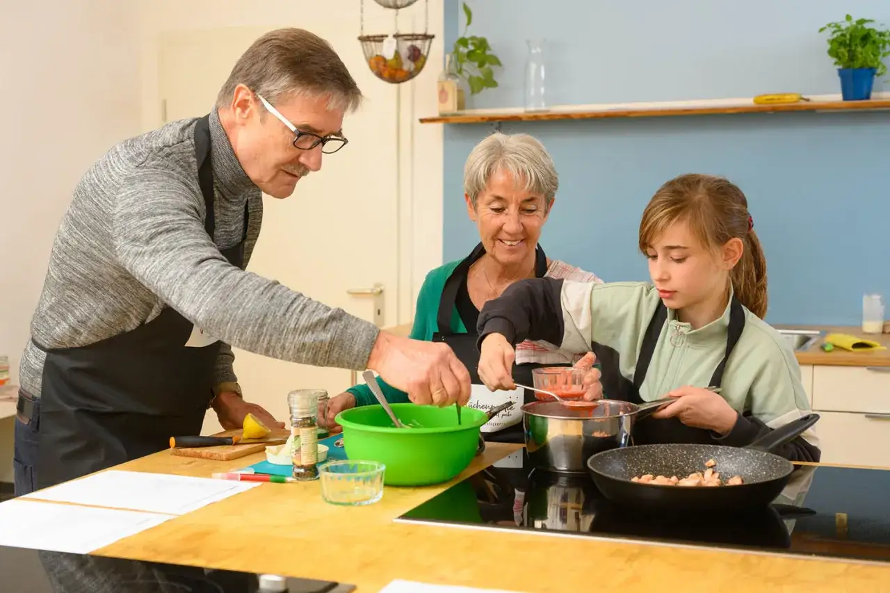 Familie kocht gemeinsam am Wochenende. Großvater, Großmutter und Enkelin bereiten eine Mahlzeit zu.