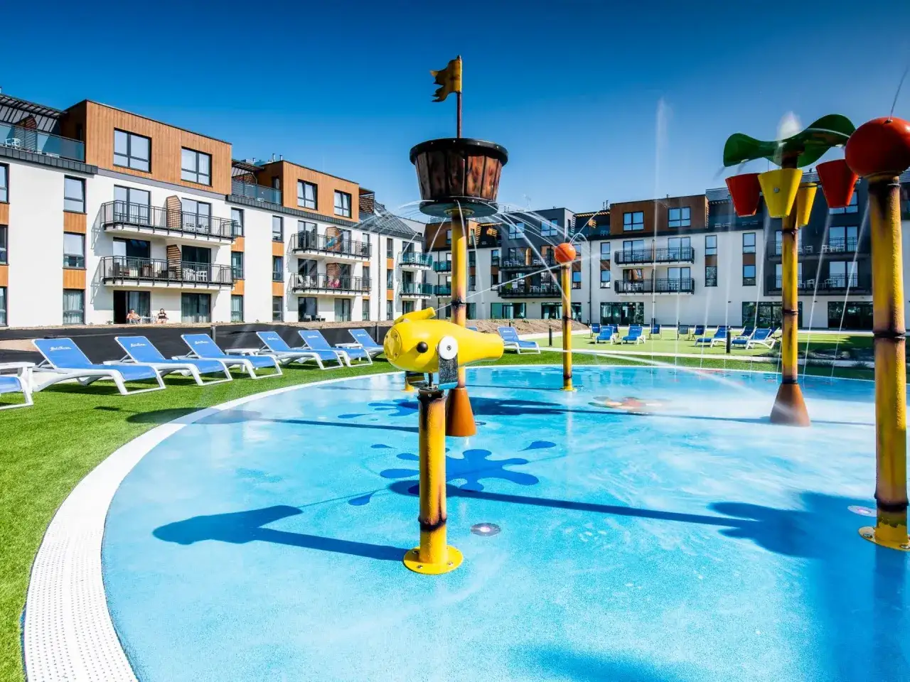 Wesoła wodna zabawa na placu zabaw w Bel Mare Resort Międzyzdroje. Kolorowe zraszacze i basenik dla dzieci.
