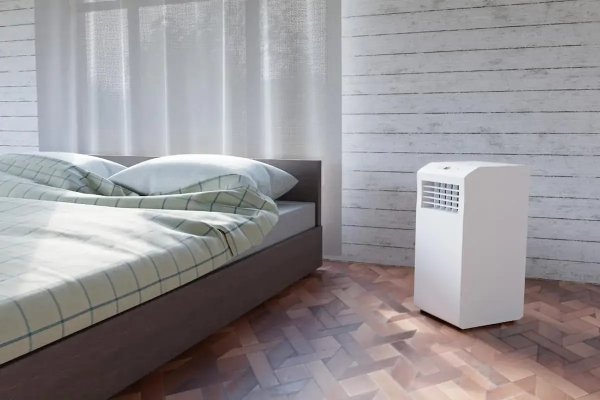 Un système split sans évacuation blanc, discret, dans une chambre avec un lit douillet et des rideaux légers.