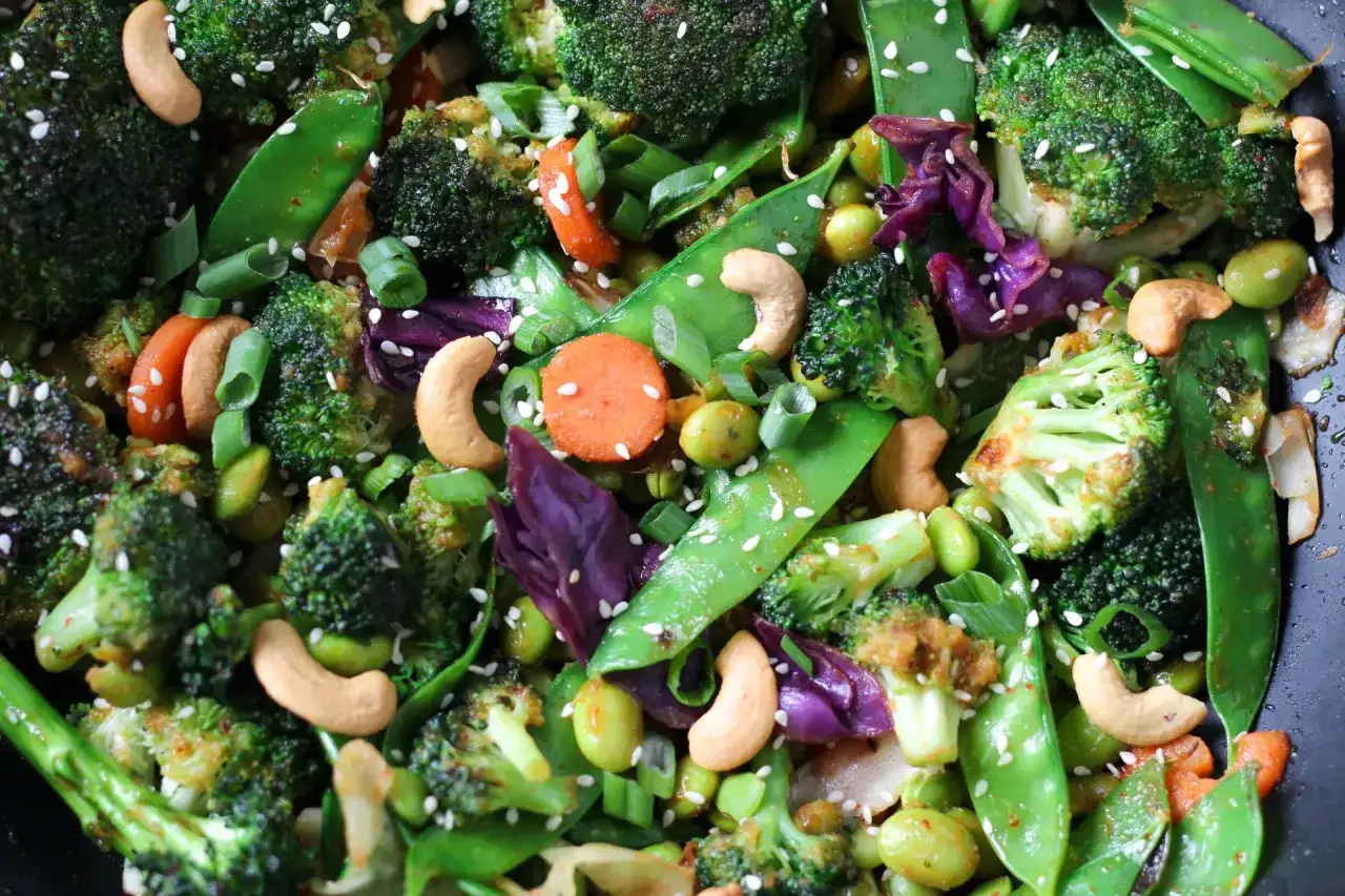Un colorido salteado de verduras con brócoli, guisantes, zanahoria, edamame y anacardos, espolvoreado con semillas de sésamo.