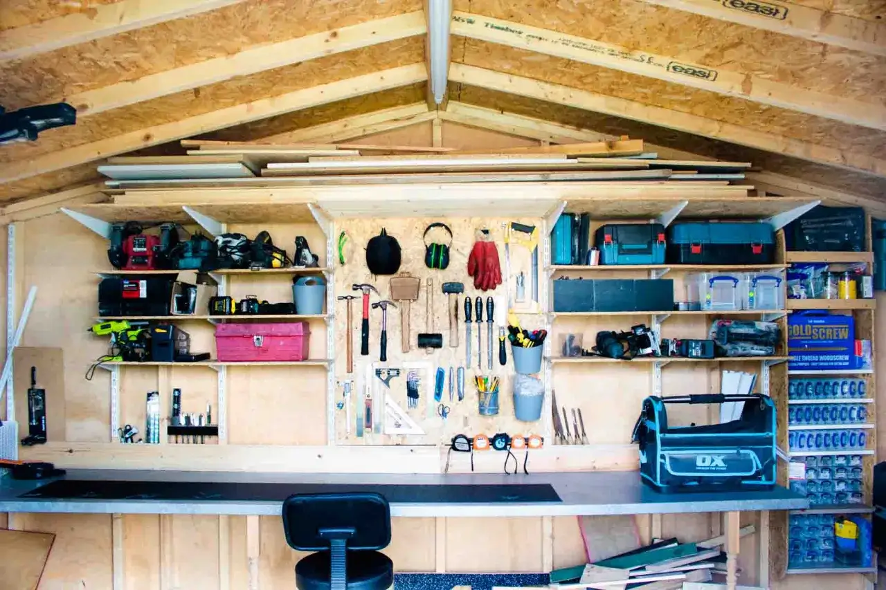 Werkstatt im Gartenhaus: Werkzeuge, Maschinen und Material für den Innenausbau sind ordentlich an Regalen und Wänden befestigt.