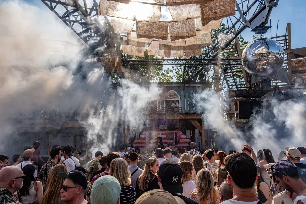 Menschenmenge bei einem Festival in den Woodlands Hildesheim, umgeben von Nebel und Lichtern.