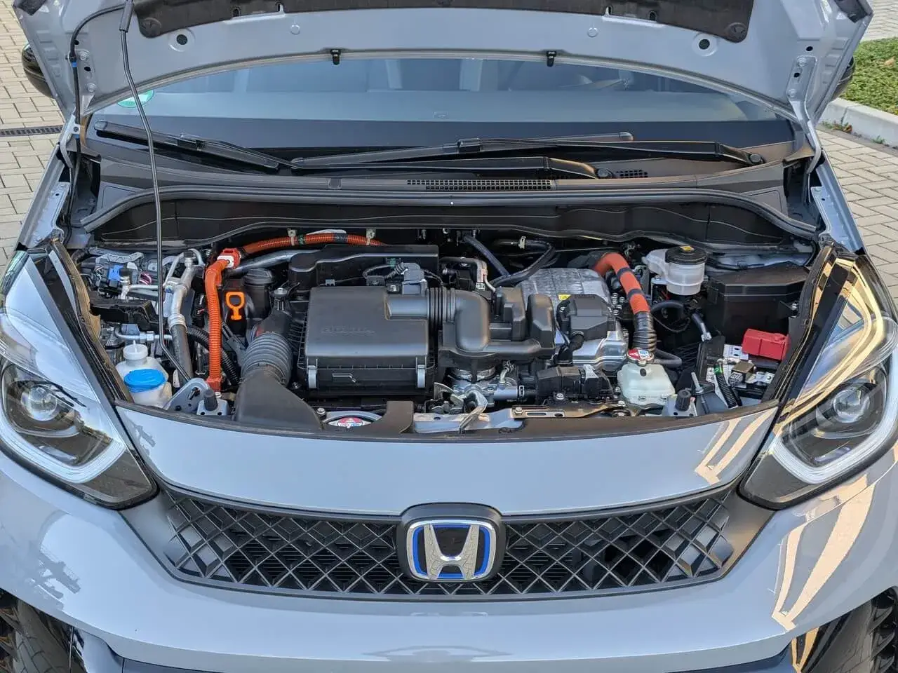 Motorraum eines Honda Jazz Hybrid. Orange Kabel deuten auf Hybridtechnik hin, die bei Honda Jazz Hybrid Probleme verursachen kann.