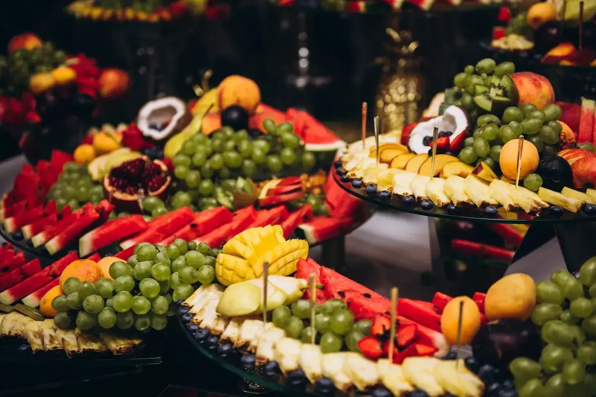 Kolorowa patera z owocami na wesele: soczyste arbuzy, winogrona, ananasy, mango i inne przysmaki.