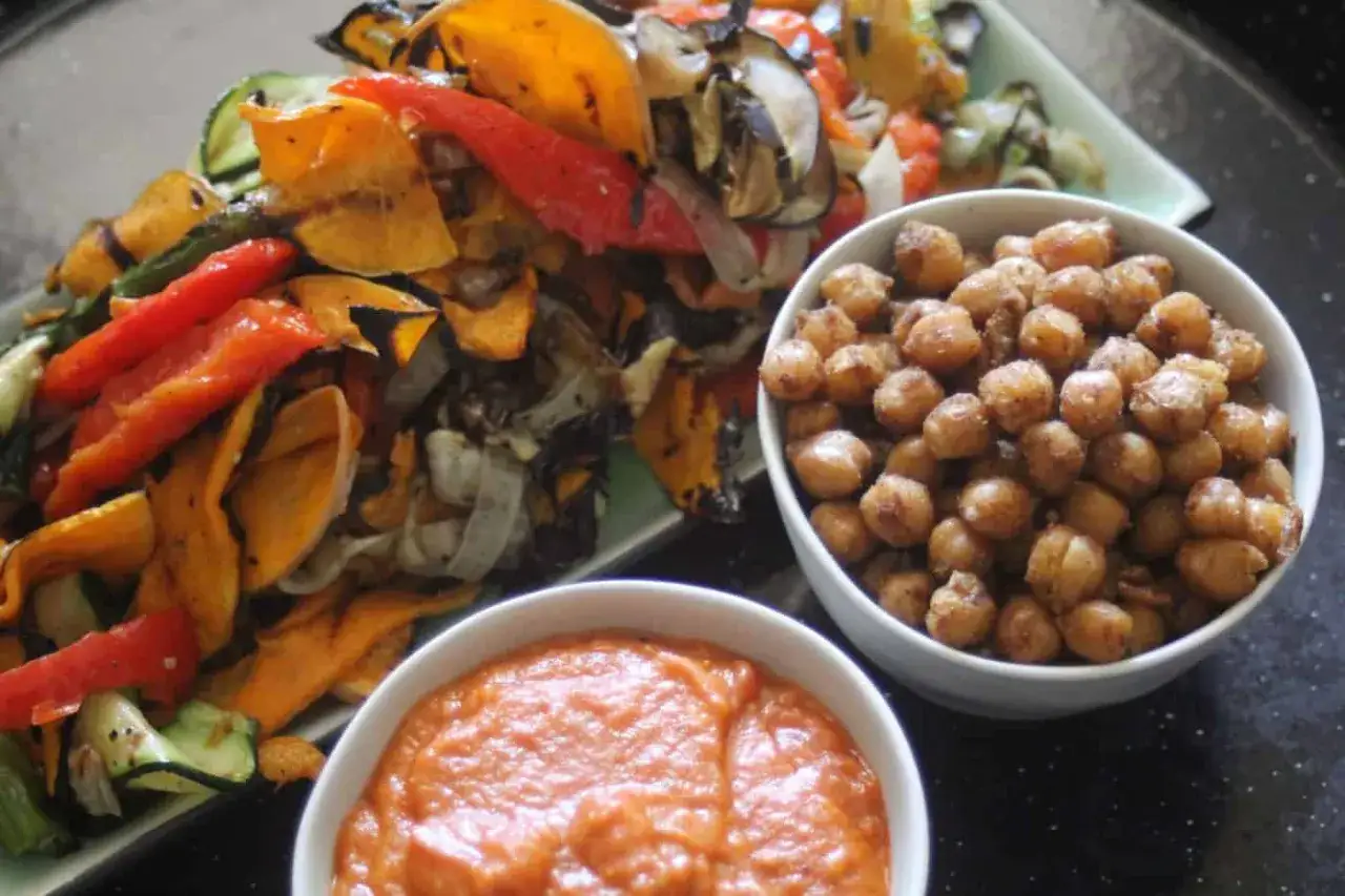Un bol de pois chiche grillé croustillants à côté de légumes rôtis et d'une sauce crémeuse.